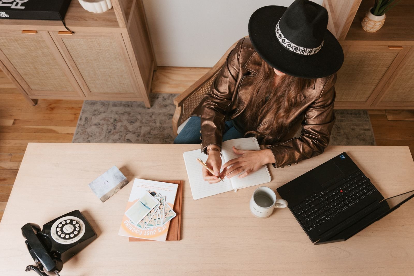 Overhead view of Kristin writing in a notebook at her desk beside her laptop