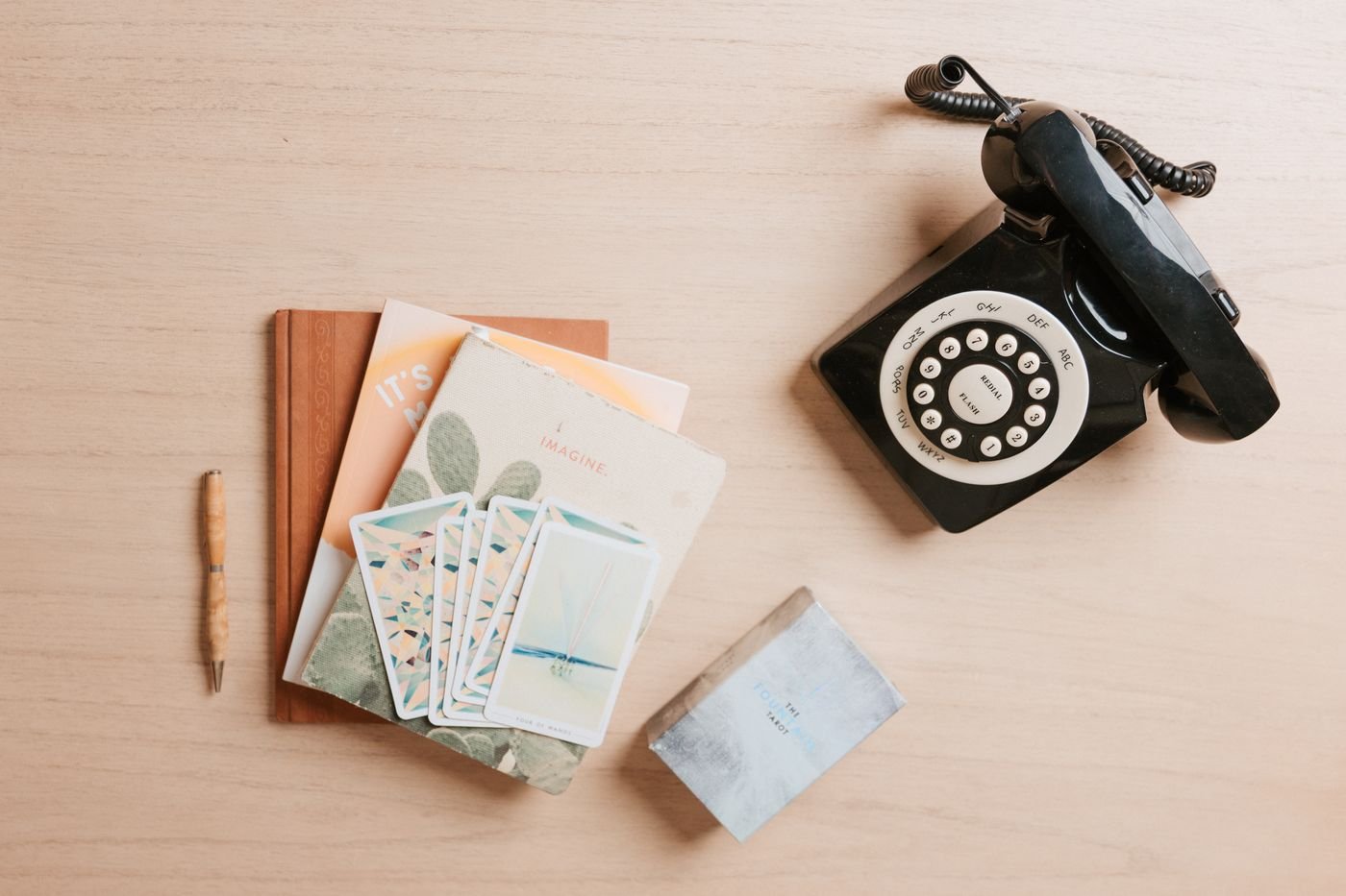 Flat lay of notebooks, planning cards and a vintage rotary phone on a wooden desk