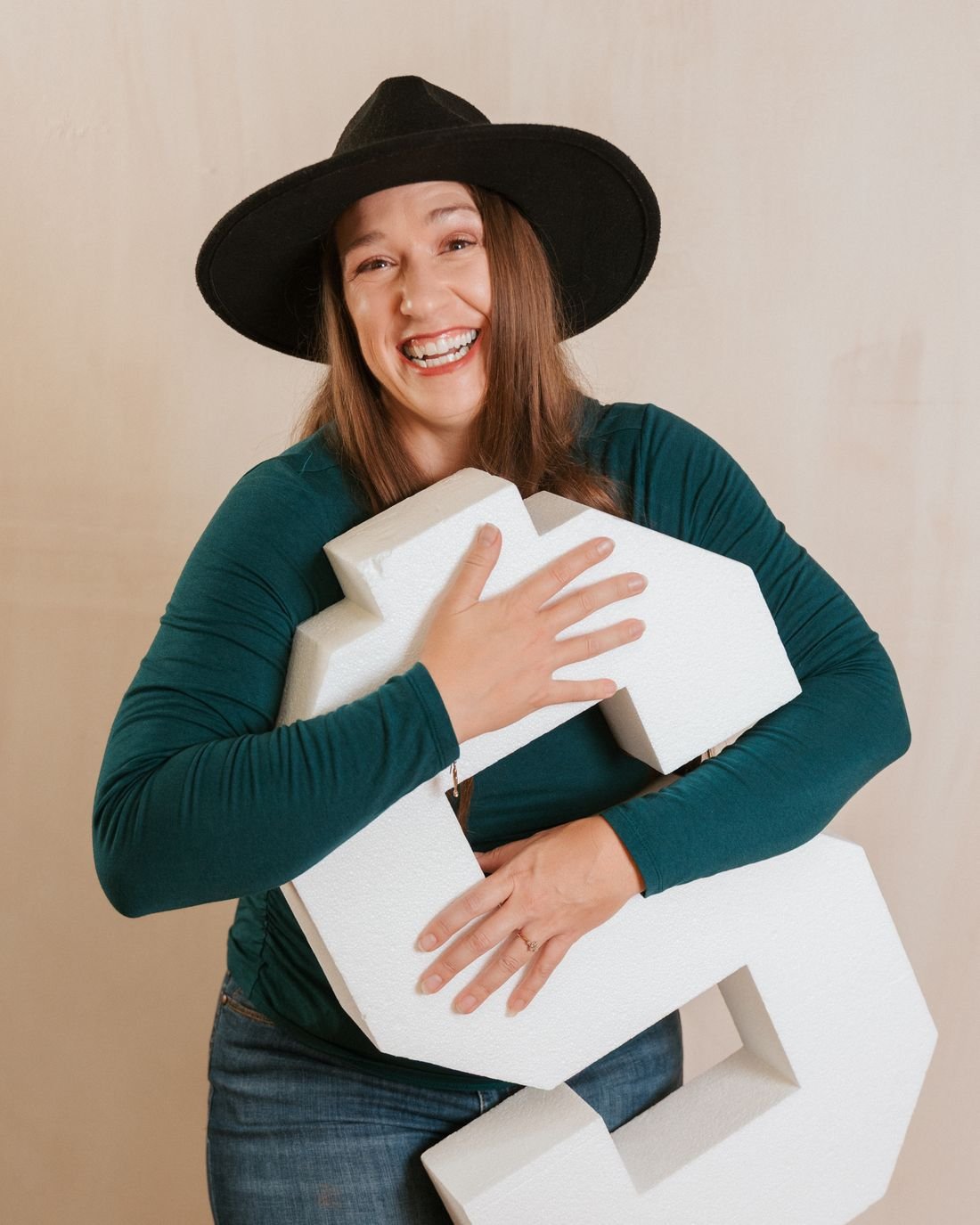 Kristin Winstanley laughing while hugging a giant white dollar sign