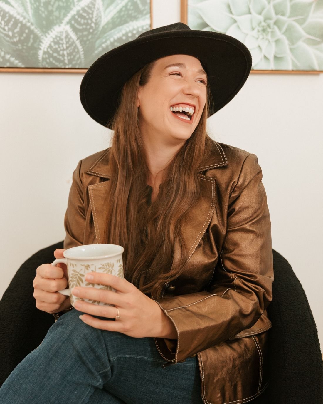 Kristin Winstanley laughing in an armchair, holding a coffee mug